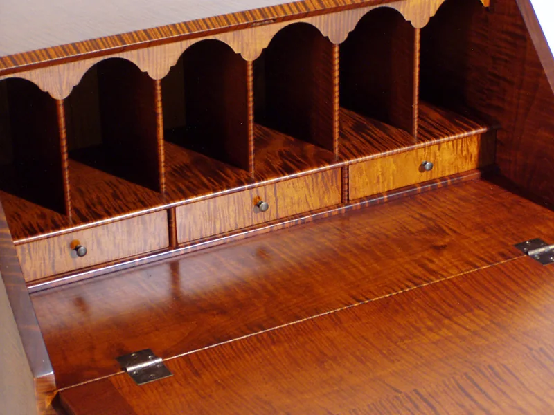 Pigeonhole compartments and dovetailed drawers inside a curly maple desk