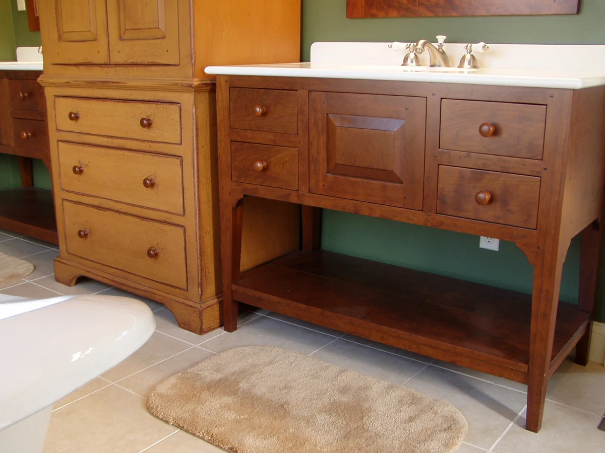 Cherry bath vanity with an open lower shelf and copper basin