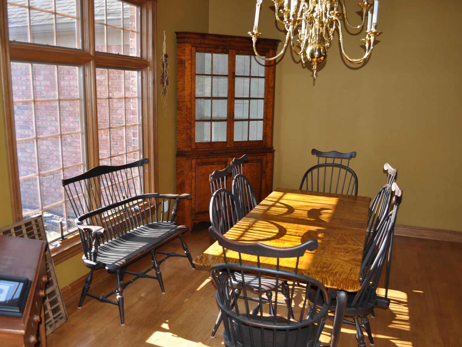 Windsor chairs drawn up to a curly maple dining table in morning light