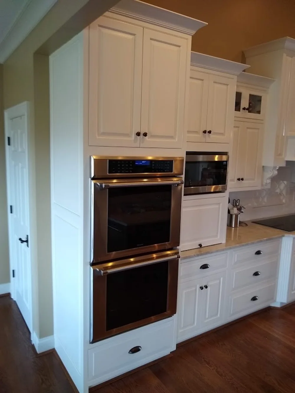 Hand-painted kitchen joinery with integrated wall ovens and a tall larder case